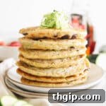Zucchini pancakes on a plate with shredded zucchini on top.