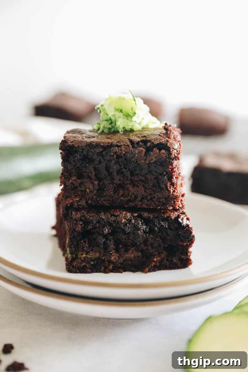 Zesty Zucchini Brownies 2 Six perfectly baked zucchini brownies, rich in color, are neatly stacked on pristine white plates, highlighting their appealing texture.