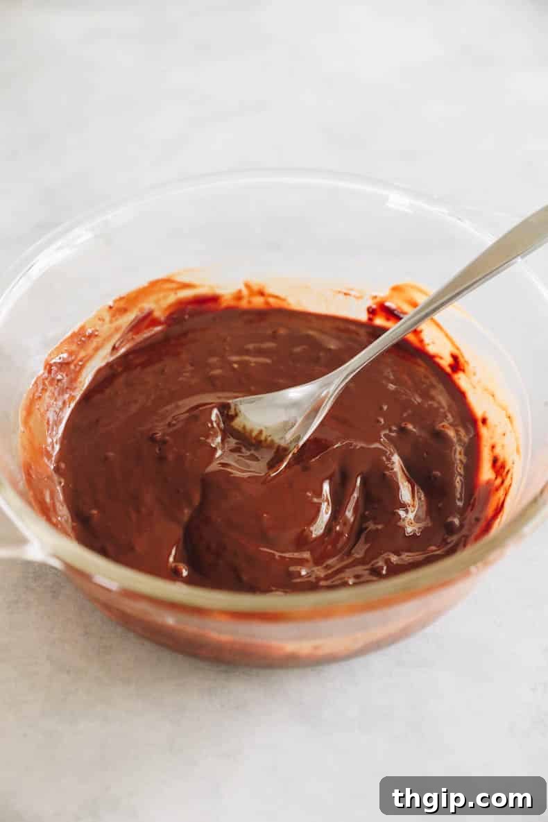 Zesty Zucchini Brownies 4 A glistening mixture of melted dark chocolate and butter is shown in a clear glass bowl, indicating a smooth, well-combined consistency.