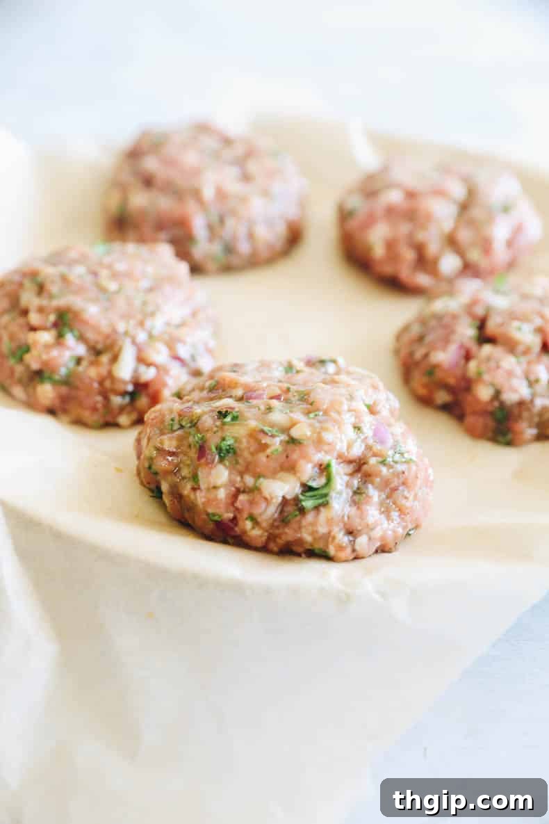 Perfect Turkey Burgers Every Time 4 raw turkey patties on a plate with parchment paper
