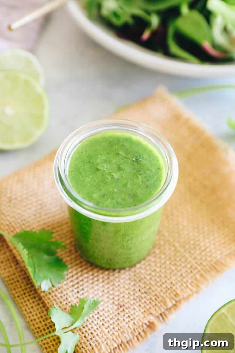 Vibrant Cilantro Lime Dressing 7 Vibrant green cilantro lime dressing poured into a clear glass jar, set against a rustic background, ready for serving.