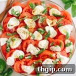 A beautifully presented tomato burrata salad on a large plate, featuring fresh tomatoes, creamy burrata cheese, aromatic basil, a drizzle of olive oil, and a sprinkle of salt and pepper.