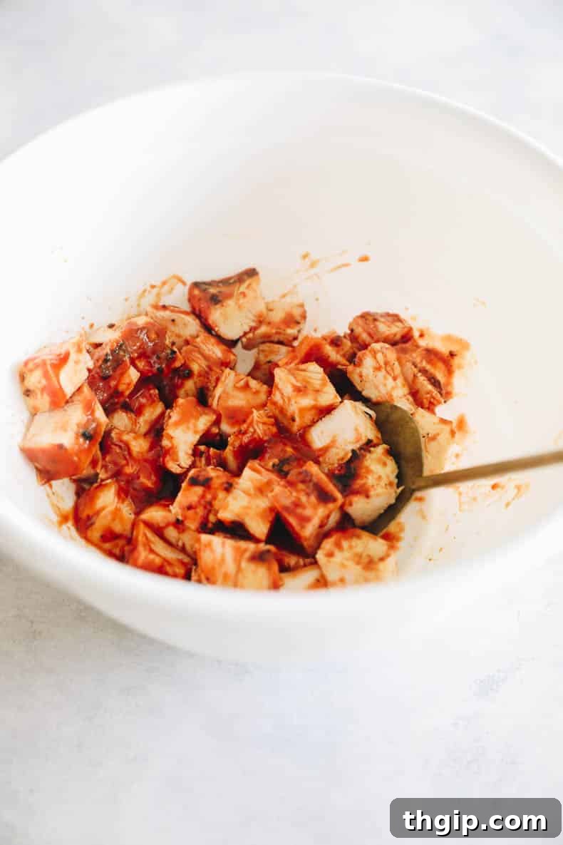 BBQ chicken coated in BBQ sauce in a white bowl.
