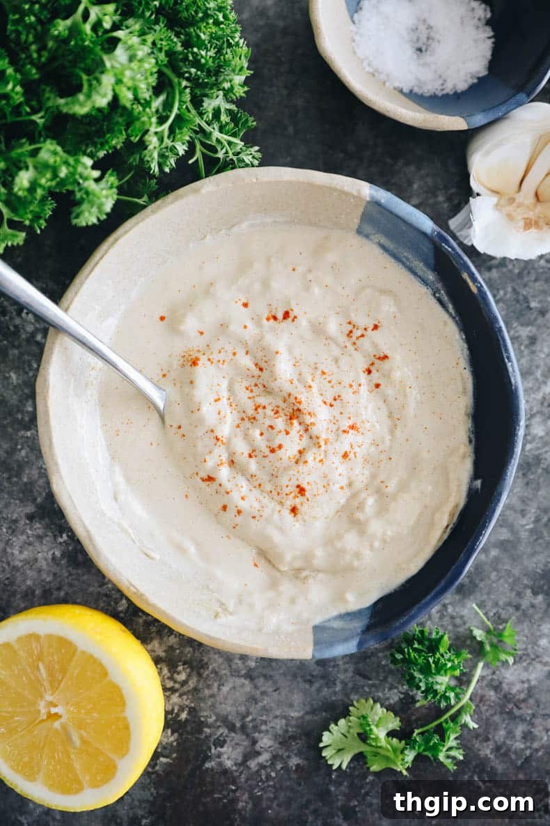 A small bowl of creamy, light-colored tahini sauce, perfectly drizzled and ready to be served with the Mediterranean bowl.