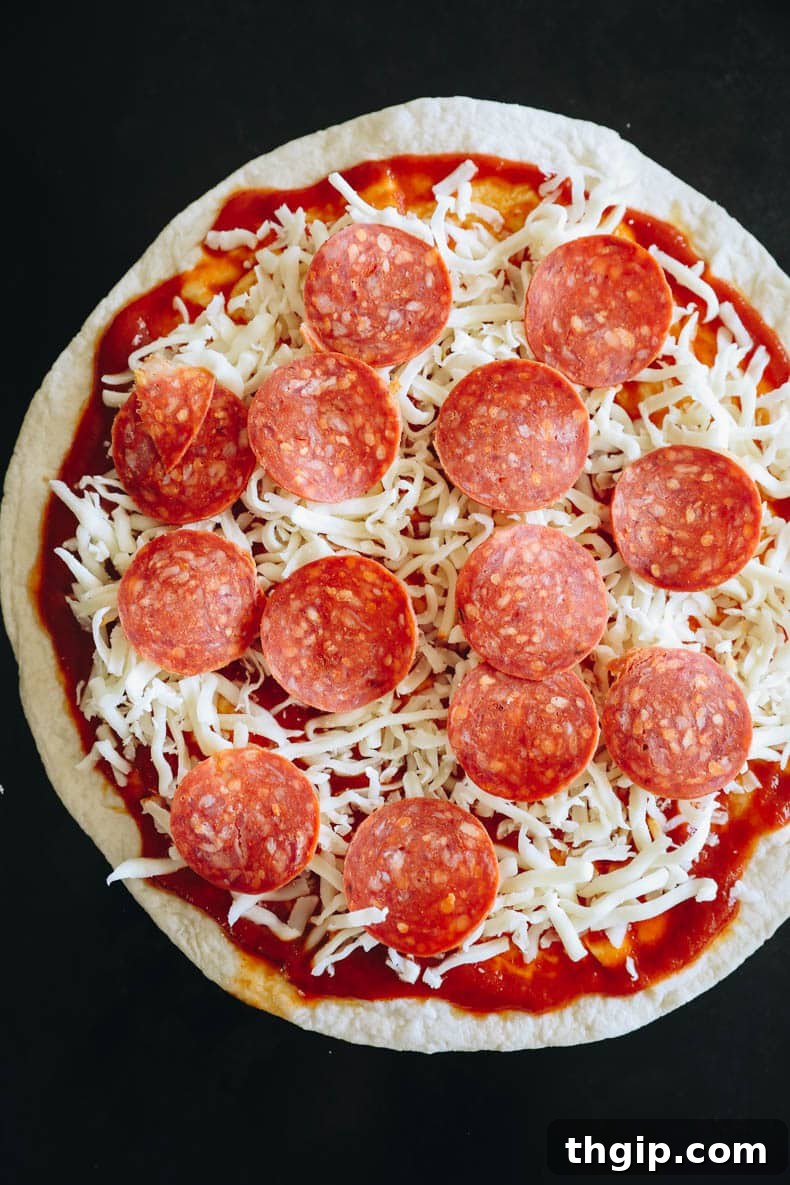 Crispy Tortilla Pizza 3 Unbaked tortilla pizza with sauce, cheese, and pepperoni on a baking sheet, ready for the oven.