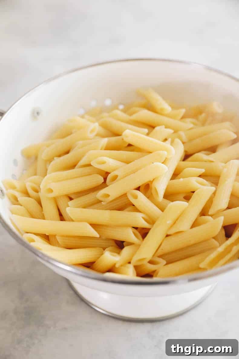 Freshly cooked penne pasta, perfectly al dente, strained in a colander and ready for the next step of the recipe.
