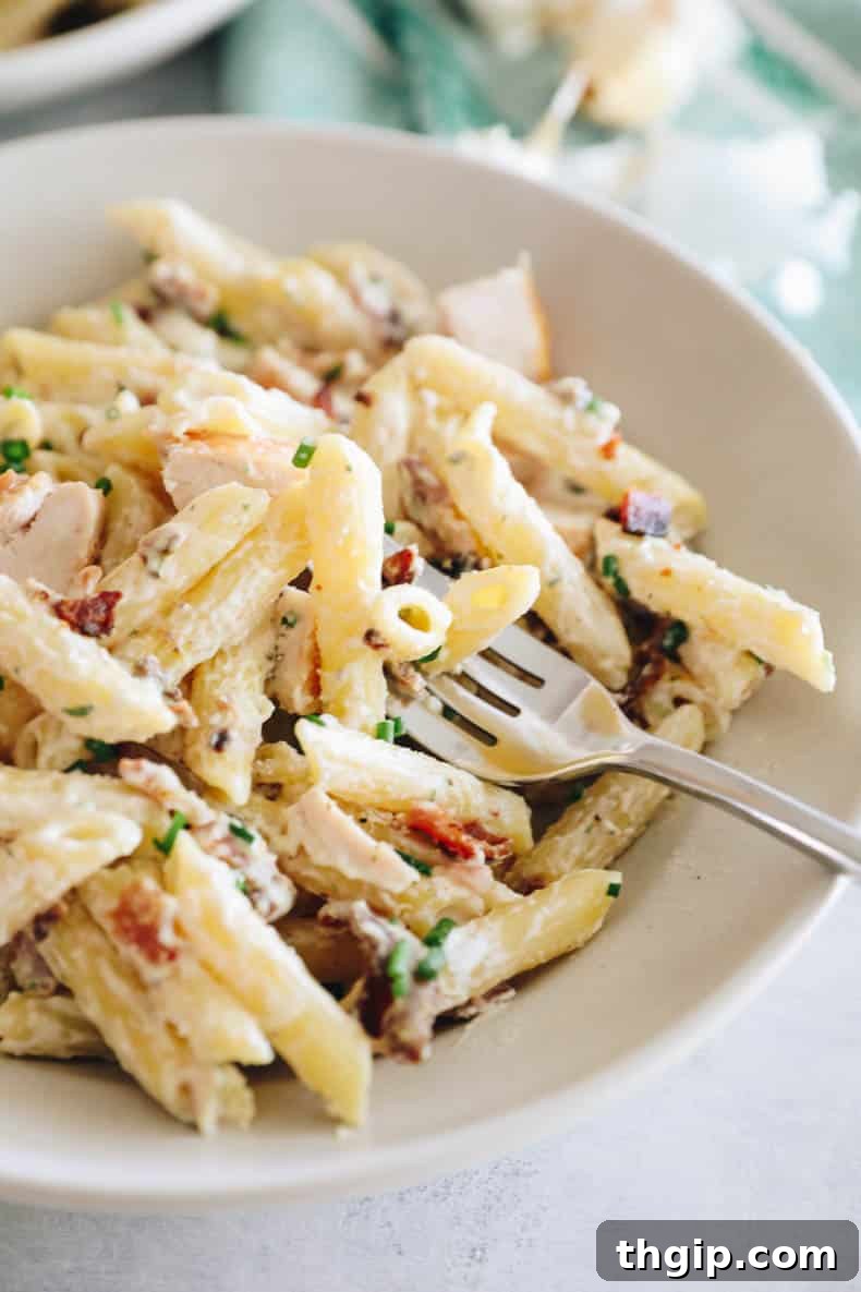 A close-up shot of the finished chicken bacon ranch pasta in a large pot, garnished with fresh chives, showcasing the creamy texture and delicious ingredients.