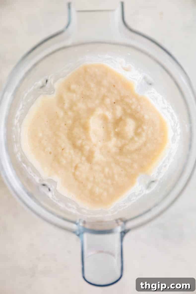 A smooth and vibrant peach smoothie, freshly blended and contained within a high-speed blender, ready to be poured into glasses.