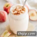 A vibrant peach smoothie served in a clear mason jar, topped with a dash of cinnamon for a delicious finish.