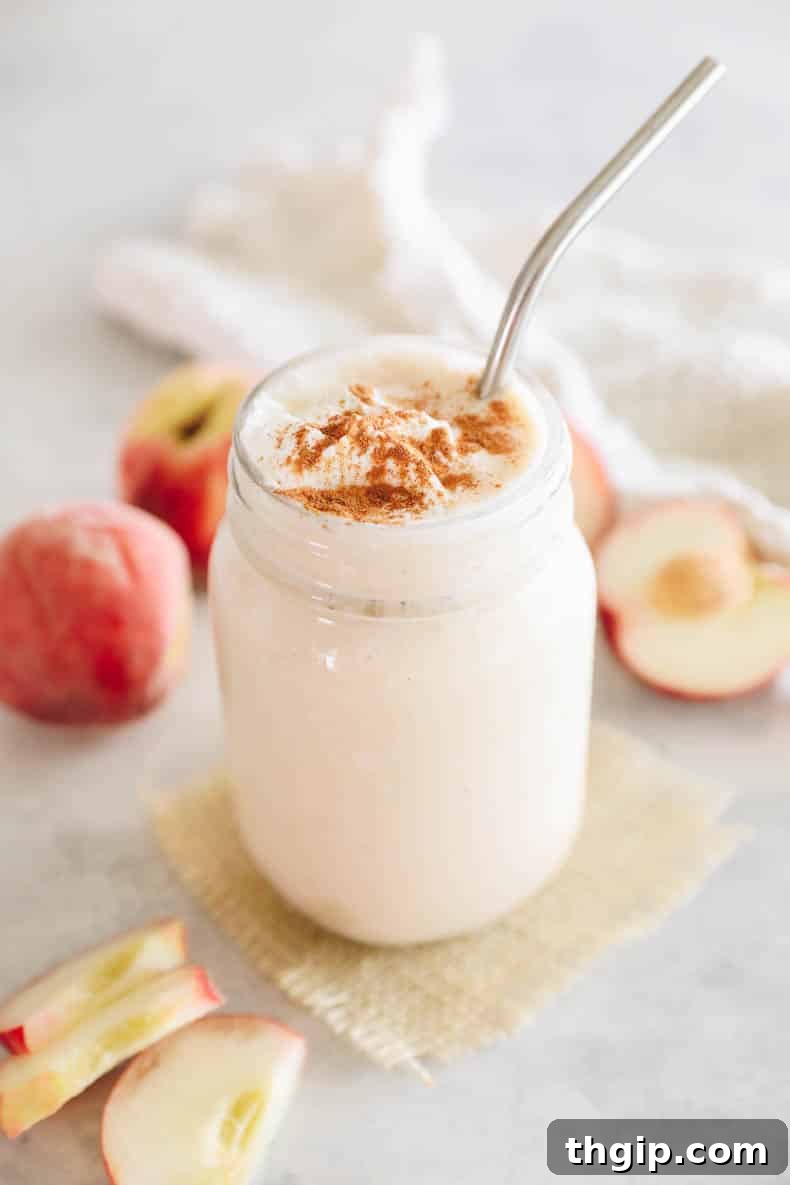 A close-up shot of a refreshing peach smoothie in a clear mason jar, sprinkled with cinnamon for extra flavor and visual appeal.