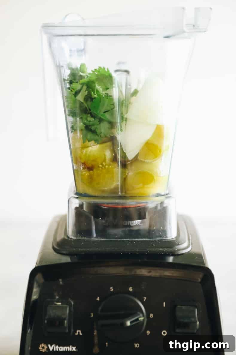 Unleash Tomatillo Magic 12 Delicious Ways 3 Straight on shot of a Vitamix blender filled with green salsa ingredients.