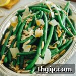 green bean salad with shaved parmesan and toasted almonds on a silver platter.