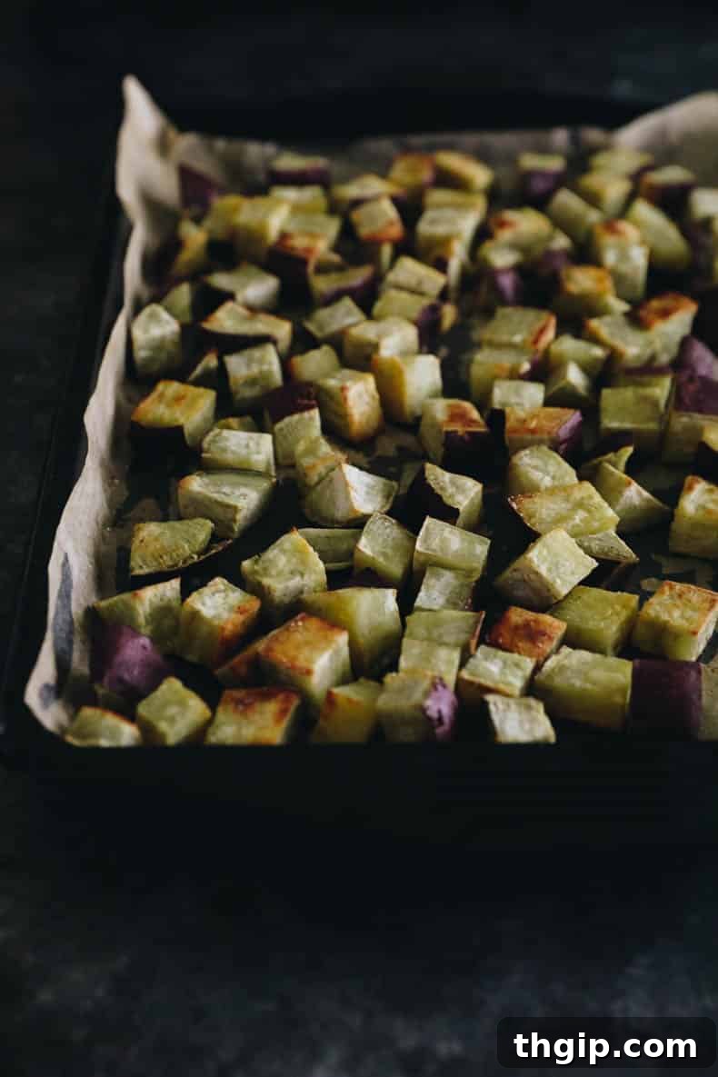 Sweet & Creamy Roasted Japanese Sweet Potato 4 Cubed Japanese sweet potatoes spread in a single layer on a parchment-lined sheet pan, ready for roasting.