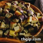 Roasted Japanese sweet potato in a large brown bowl topped with a miso tahini dressing, ready to be served.