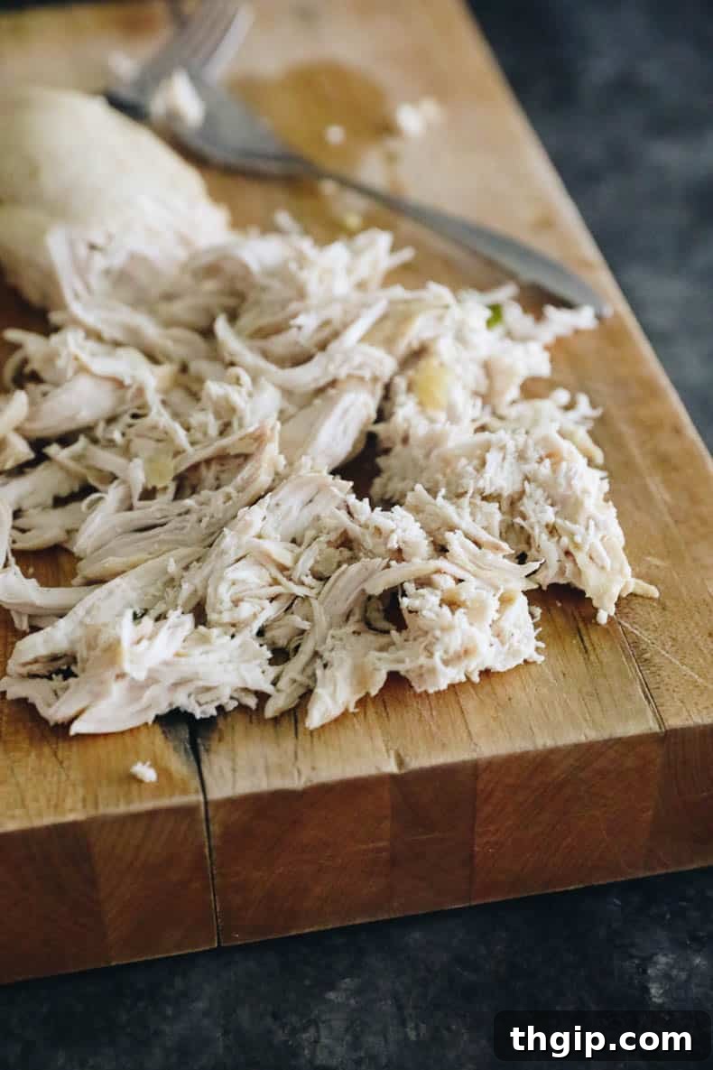 Tender, shredded chicken breast resting on a cutting board, ready to be added back into the soup.