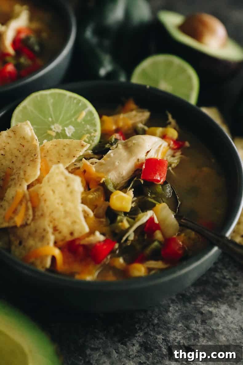 A close-up image of chicken poblano soup in a blue ceramic bowl, highlighting the rich broth and ingredients.