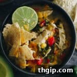 chicken poblano soup with a lime, tortilla chips and shredded cheese in a navy blue bowl.