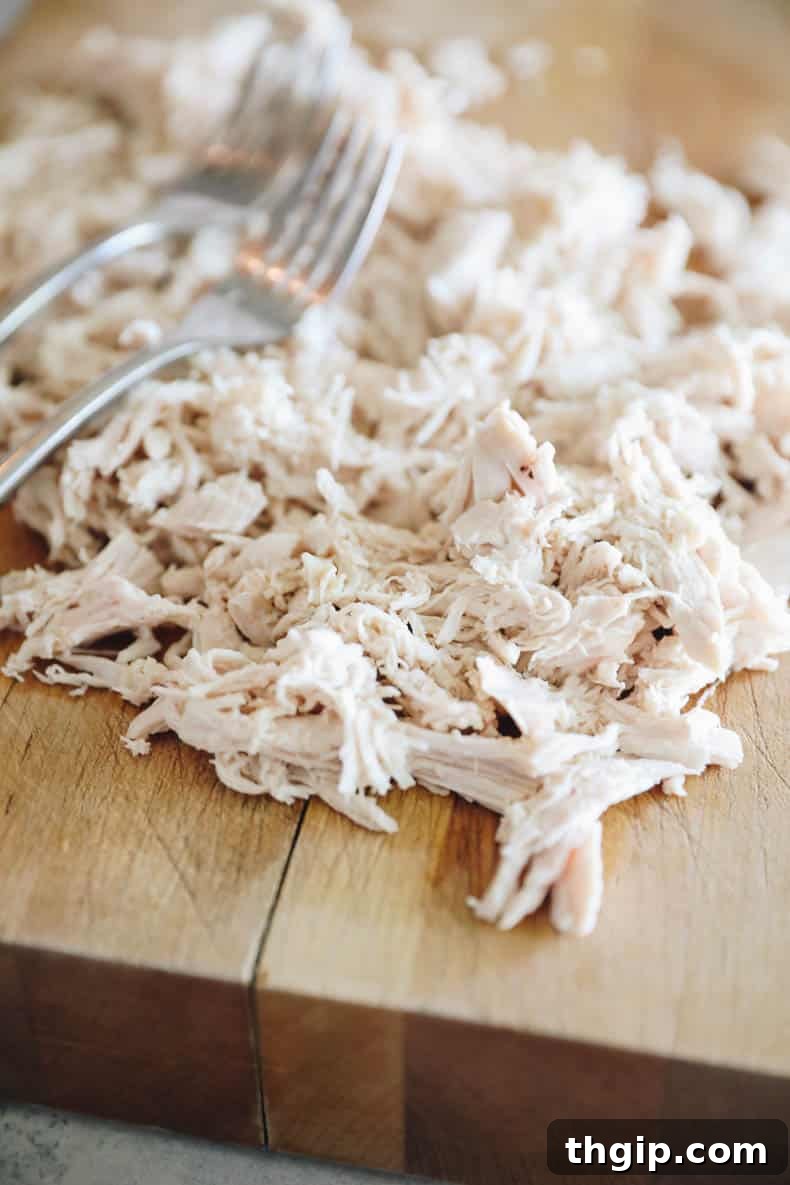 Creamy Chicken Wild Rice Delight 5 Perfectly shredded tender chicken meat laid out on a cutting board, ready to be incorporated back into the creamy wild rice soup.