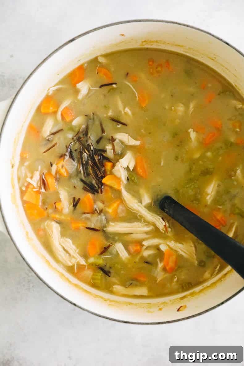 Creamy Chicken Wild Rice Delight 6 A large white Dutch oven filled with simmering, creamy chicken wild rice soup, showing the rich, hearty texture and wholesome ingredients.