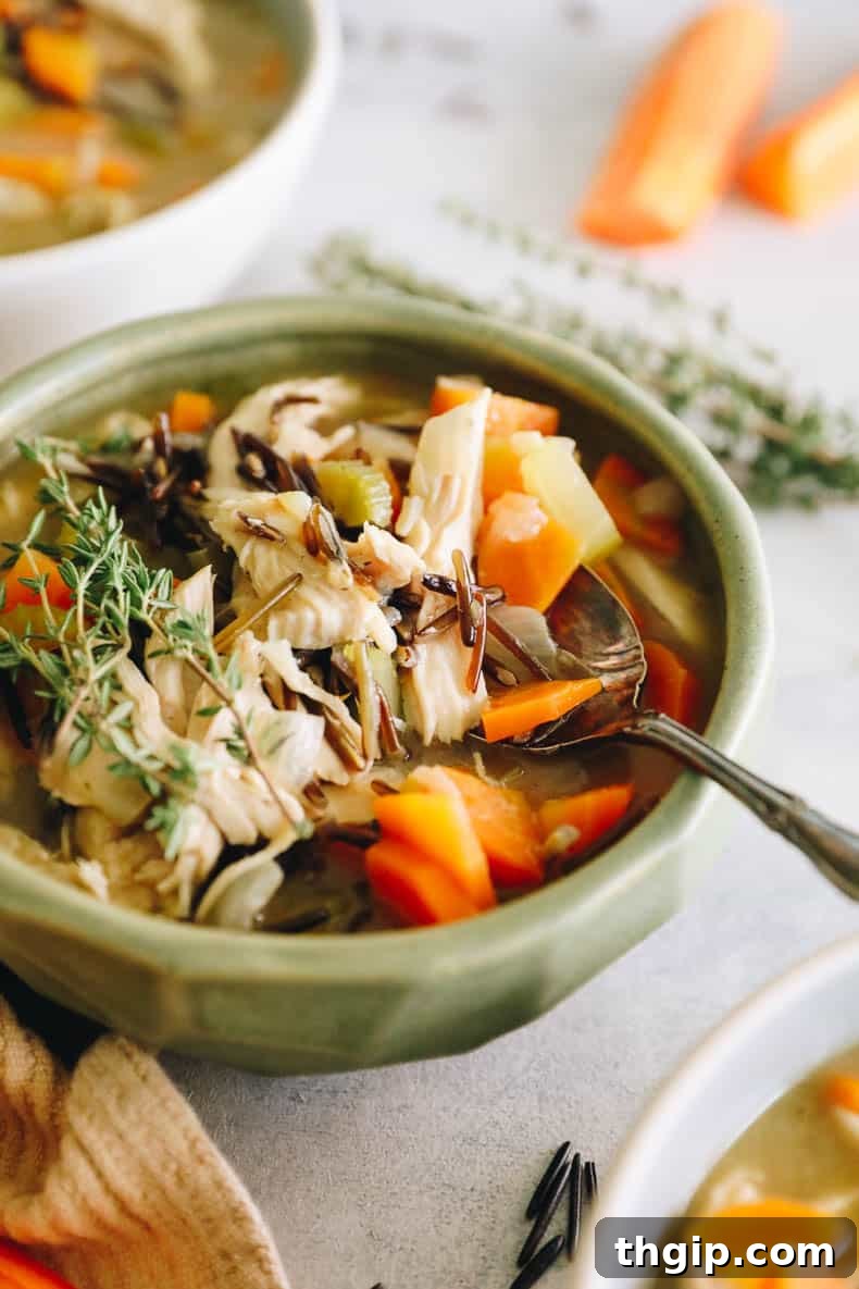 Creamy Chicken Wild Rice Delight 7 A close-up shot of a cozy green bowl brimming with creamy chicken and wild rice soup, accompanied by a spoon, highlighting its comforting appeal.