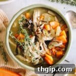 Large overhead image of a bowl of creamy chicken and wild rice soup, garnished with fresh herbs and cooked carrots.