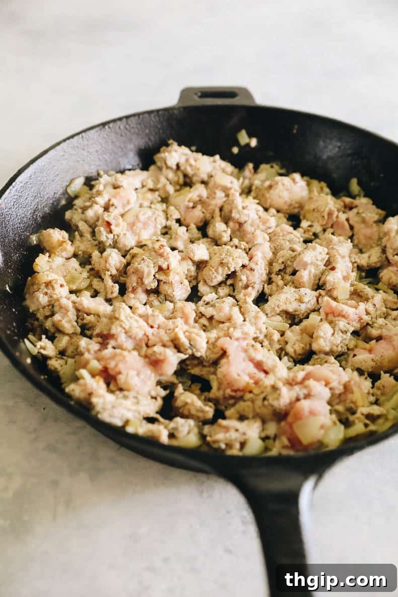 Zesty Turkey Tacos 3 Ground turkey and chopped onion cooking in a cast-iron skillet, creating a flavorful base for tacos.