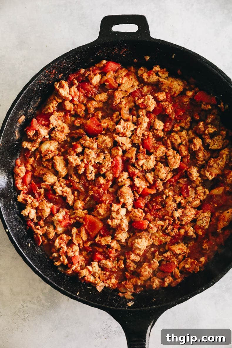 Zesty Turkey Tacos 4 Savory ground turkey taco meat simmering with diced tomatoes and spices in a cast-iron skillet.