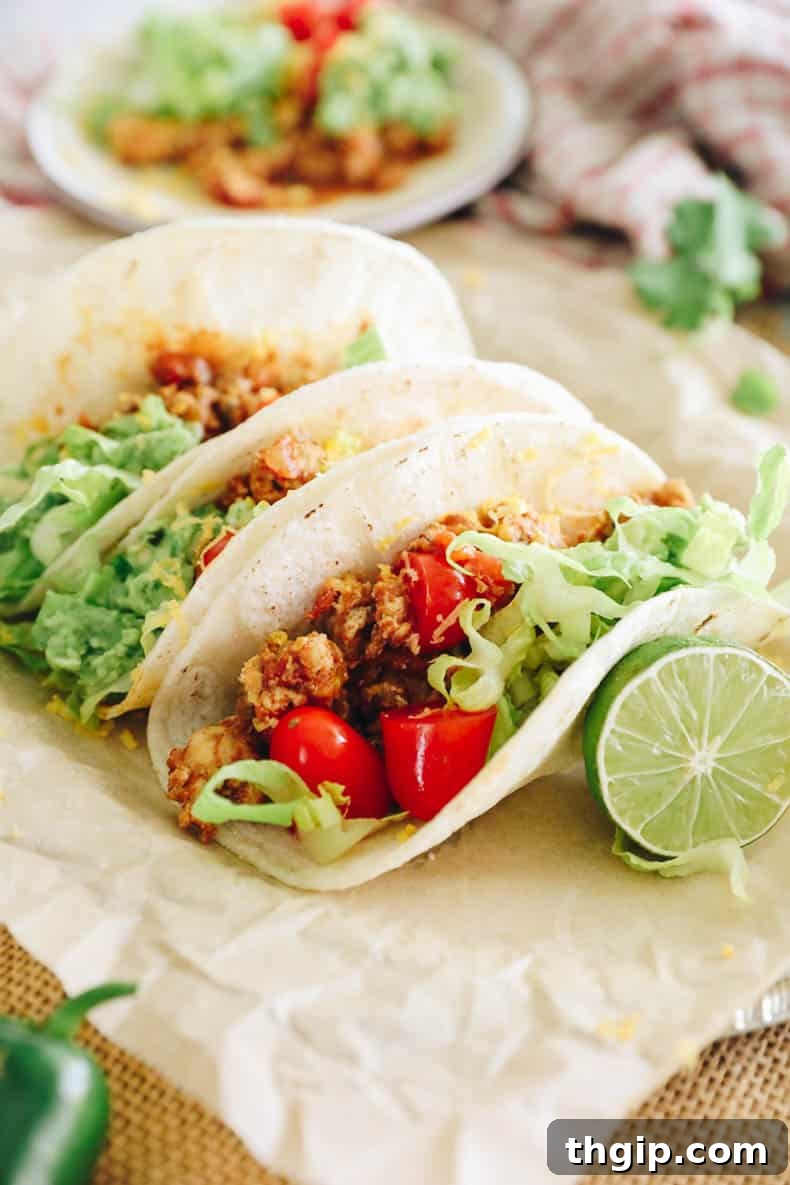 Zesty Turkey Tacos 5 Line of freshly assembled turkey tacos with various colorful toppings on a parchment-lined plate.