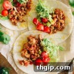 turkey tacos on white corn tortillas with ground turkey meat, tomatoes, guacamole and shredded lettuce.