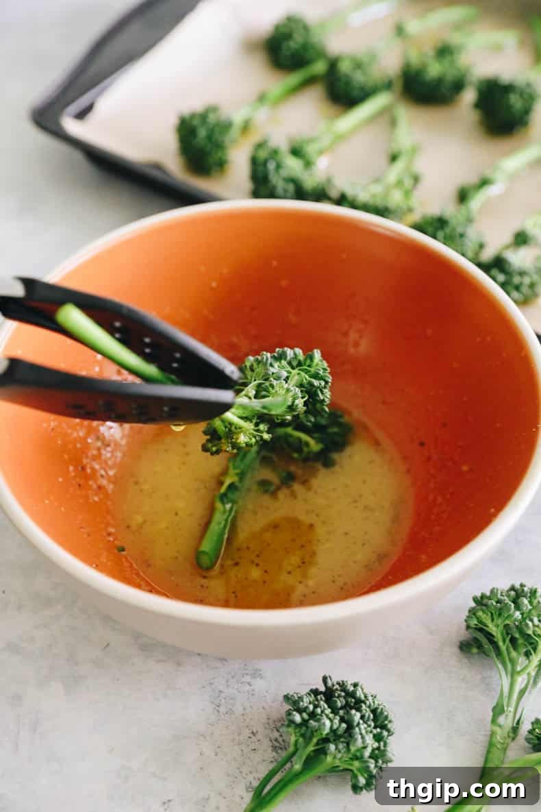 Golden Roasted Broccolini 4 dipping raw broccolini into a bowl of lemon olive oil sauce for roasting.