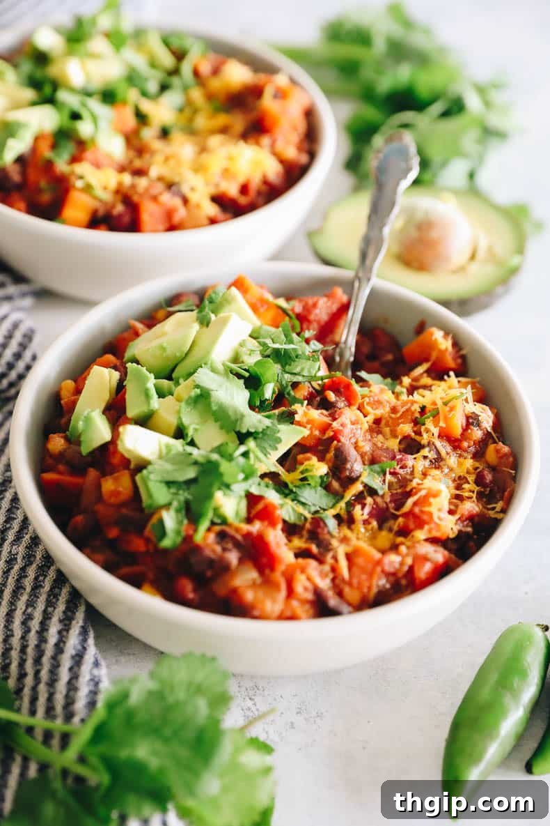 Wholesome Plant-Based Chili 2 A vibrant bowl of healthy veggie chili, richly topped with creamy avocado, fresh cilantro, and a sprinkle of shredded cheese, ready to be enjoyed.