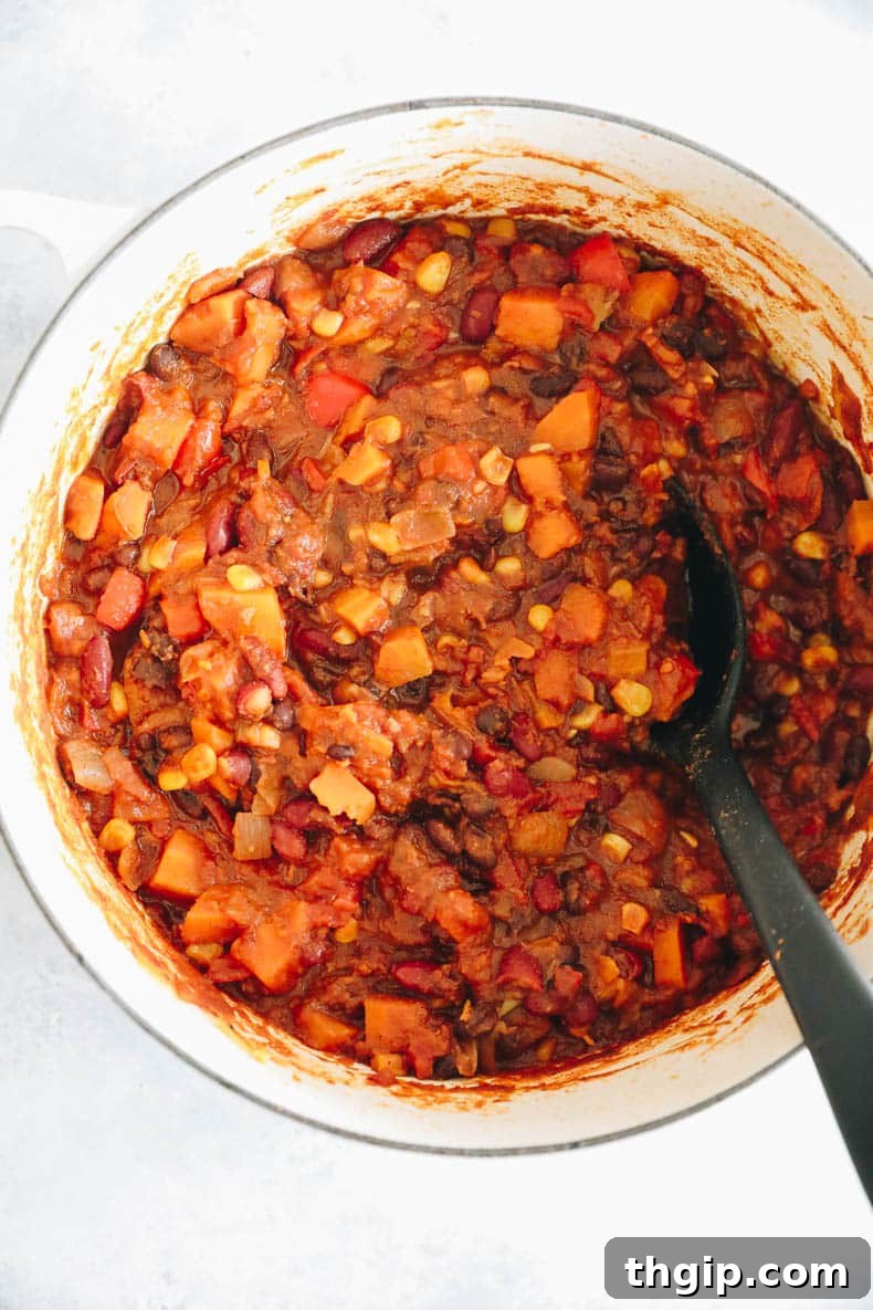 Wholesome Plant-Based Chili 4 A large white Dutch oven filled with simmering, cooked veggie chili, rich in color and texture, a testament to its healthy and delicious nature.