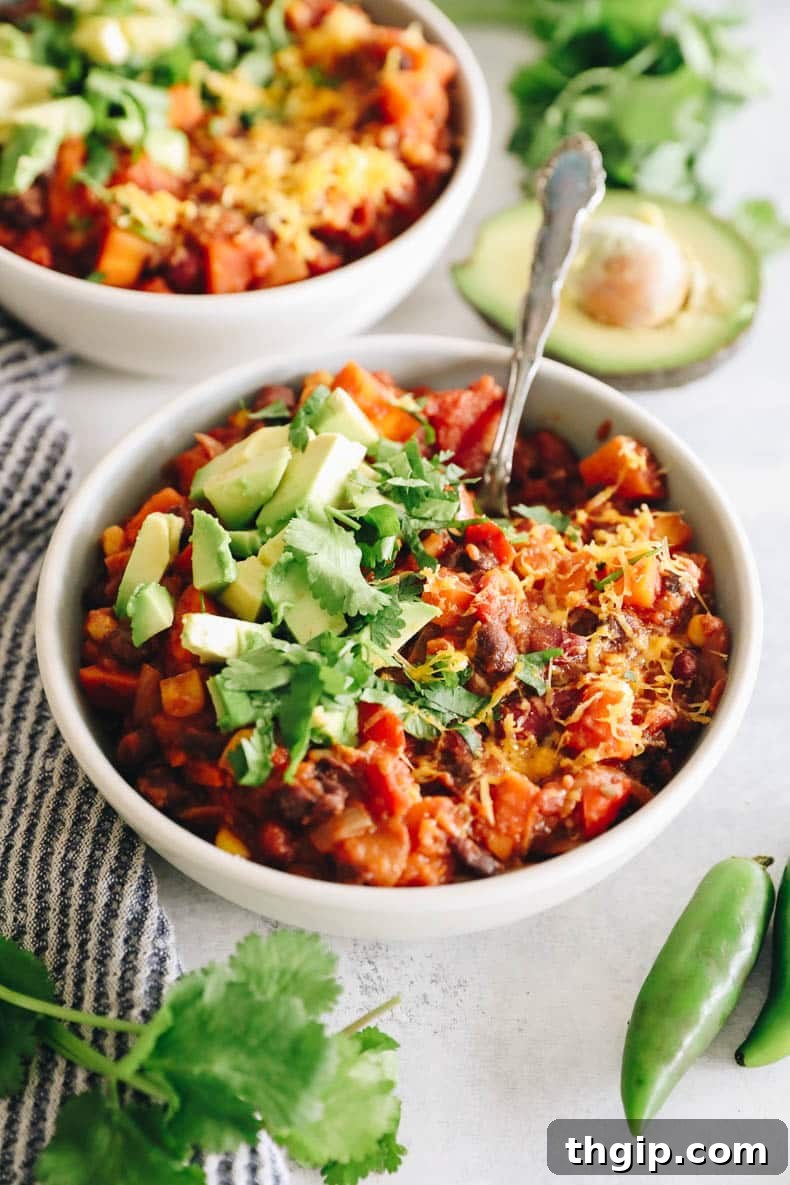 Wholesome Plant-Based Chili 5 A perfectly portioned bowl of healthy veggie chili, generously adorned with vibrant cilantro, creamy avocado slices, and a dusting of shredded cheese, ready to be devoured.