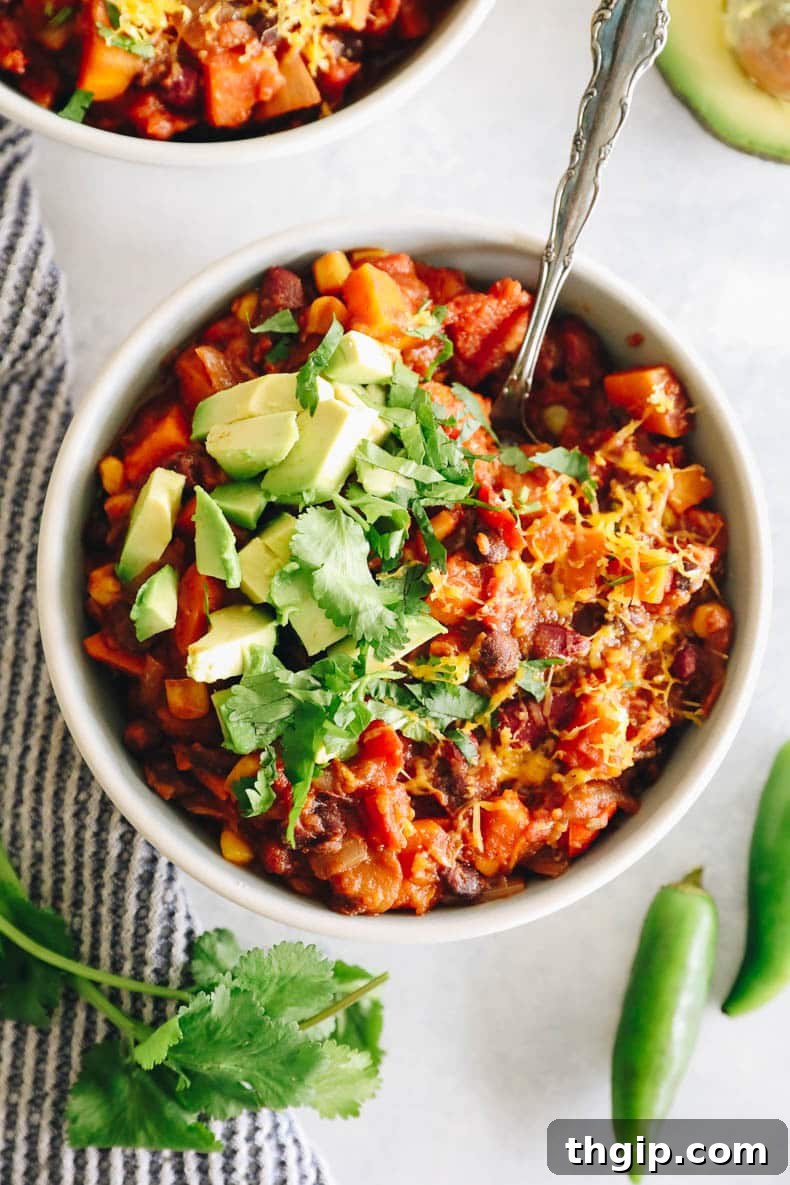Wholesome Plant-Based Chili 7 An inviting overhead view of a hearty, healthy chili recipe served in a white bowl with a silver spoon, highlighting its rich textures and appealing colors.