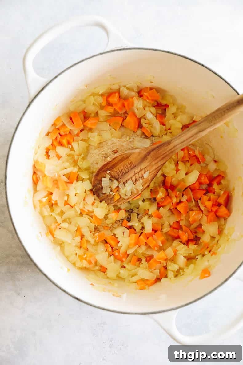 cooked onion, garlic and carrots in a white dutch oven for turkey bolognese