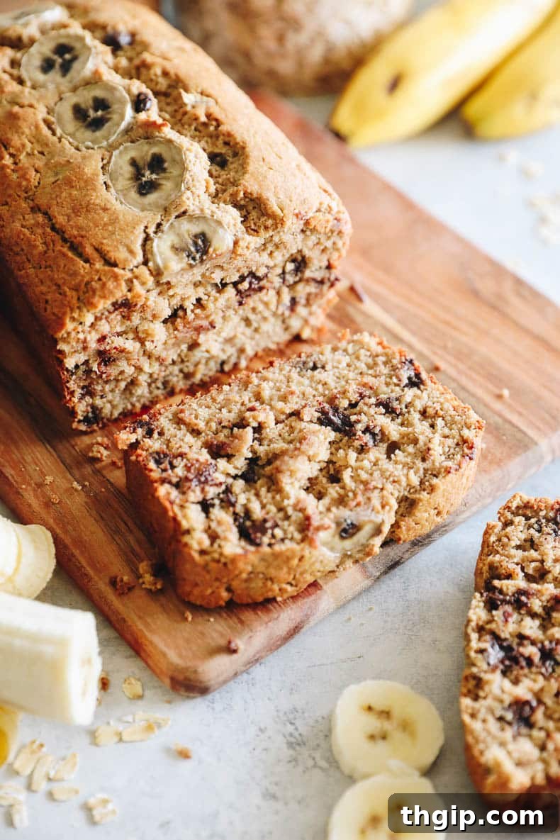 Golden Oat Flour Banana Bread 3 A perfectly baked slice of moist oat flour banana bread, showcasing its tender crumb and golden crust, resting on a wooden cutting board.