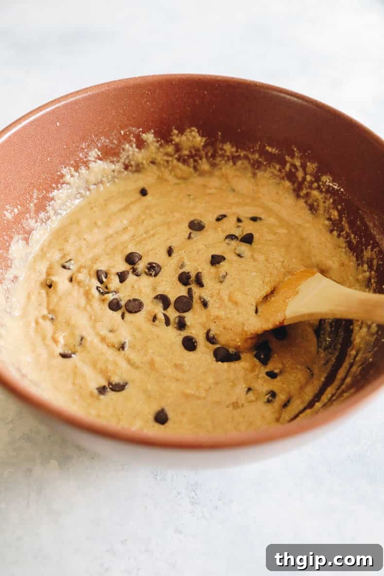 Golden Oat Flour Banana Bread 5 Moist oatmeal banana bread batter, studded with tempting chocolate chips, resting in a large brown mixing bowl, ready for baking.
