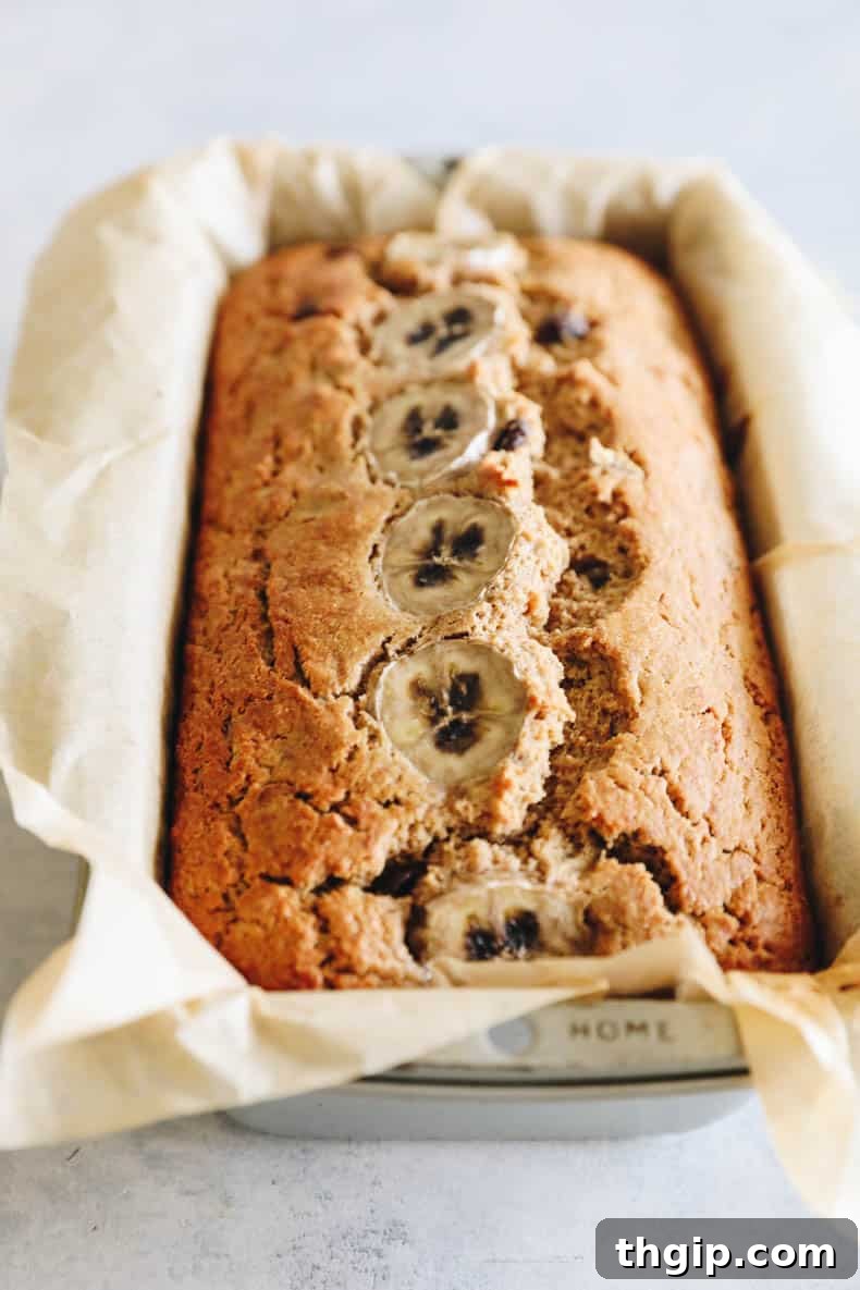 Golden Oat Flour Banana Bread 6 A freshly baked loaf of golden-brown oat flour banana bread, cooling in its loaf pan, still radiating warmth from the oven.