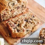 Up close image of a slice of oat flour banana bread on a cutting board, highlighting its moist texture and chocolate chips.