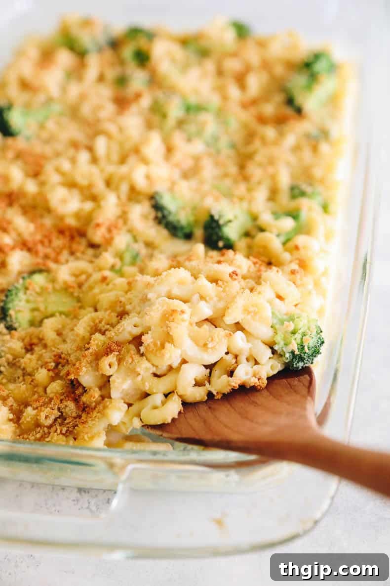 Wholesome Mac & Cheese 7 A serving spoon scooping out a generous portion of healthy baked mac and cheese from a clear baking dish.