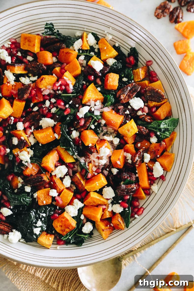 Autumn Squash Harvest Bowl 8 Upclose overhead image of a kale fall salad topped with roasted butternut squash, pomegranate seeds, candied pecans and feta cheese, ready to be served.