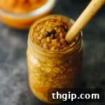 A small jar of pumpkin spice latte overnight oats, garnished with spices and a spoon, indicating a single serving.