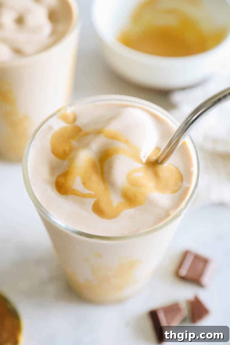 Decadent Healthy Chocolate Peanut Butter Blend 5 A close-up shot of a healthy chocolate peanut butter smoothie in a clear glass, beautifully topped with a decadent drizzle of peanut butter and a metal straw, emphasizing its rich texture and appealing presentation.