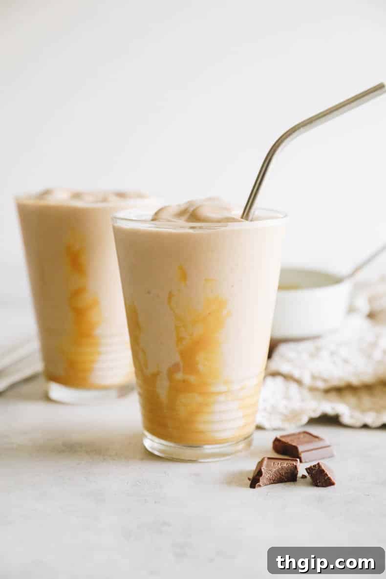 Decadent Healthy Chocolate Peanut Butter Blend 7 A beautifully presented thick chocolate peanut butter smoothie in a clear glass, featuring a rich drizzle of peanut butter and a sleek metal straw, ready to be enjoyed as a healthy and indulgent treat.