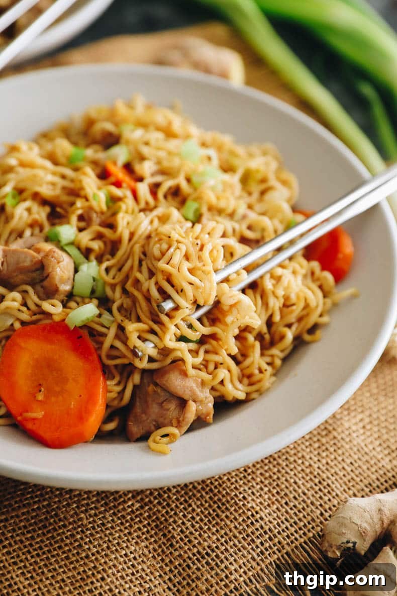 chicken chow mein in a white shallow bowl with silver chopsticks.