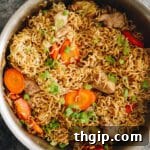 chicken chow mein cooked in a wok with carrots, green onions and cabbage.