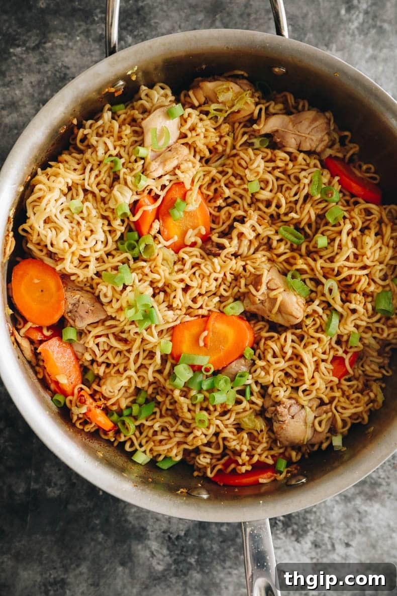 overhead image of chicken chow mein in a metal wok.