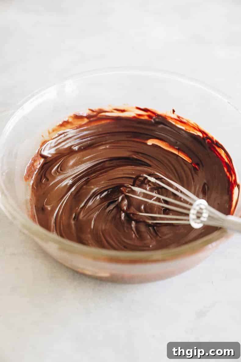 Melted dark chocolate and butter in a glass bowl with a whisk, showing the smooth, glossy mixture.