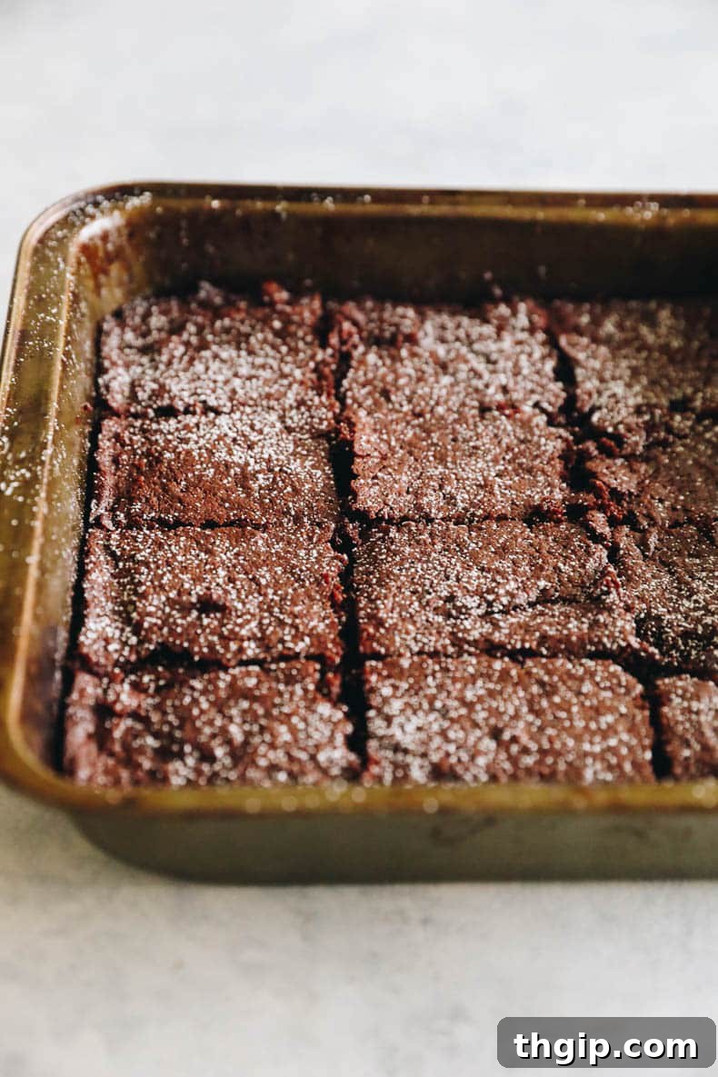 Baked almond flour brownies, dusted with powdered sugar, sitting in a baking pan.
