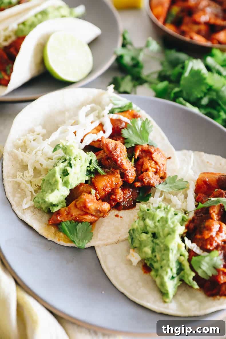 Achiote-Spiced Chicken Pastor 2 chicken al pastor with guacamole and cabbage in a taco shell.